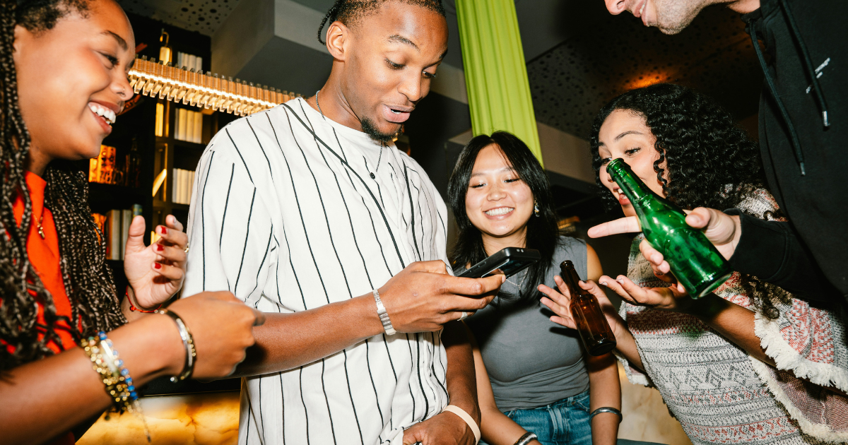 Group of Gen Z friends sharing cocktails and non-alcoholic drinks at a bar