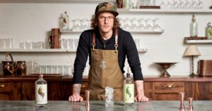 Seedlip founder Ben Branson standing behind a zinc bar with bottles of Seedlip Spice 94 and Garden 108