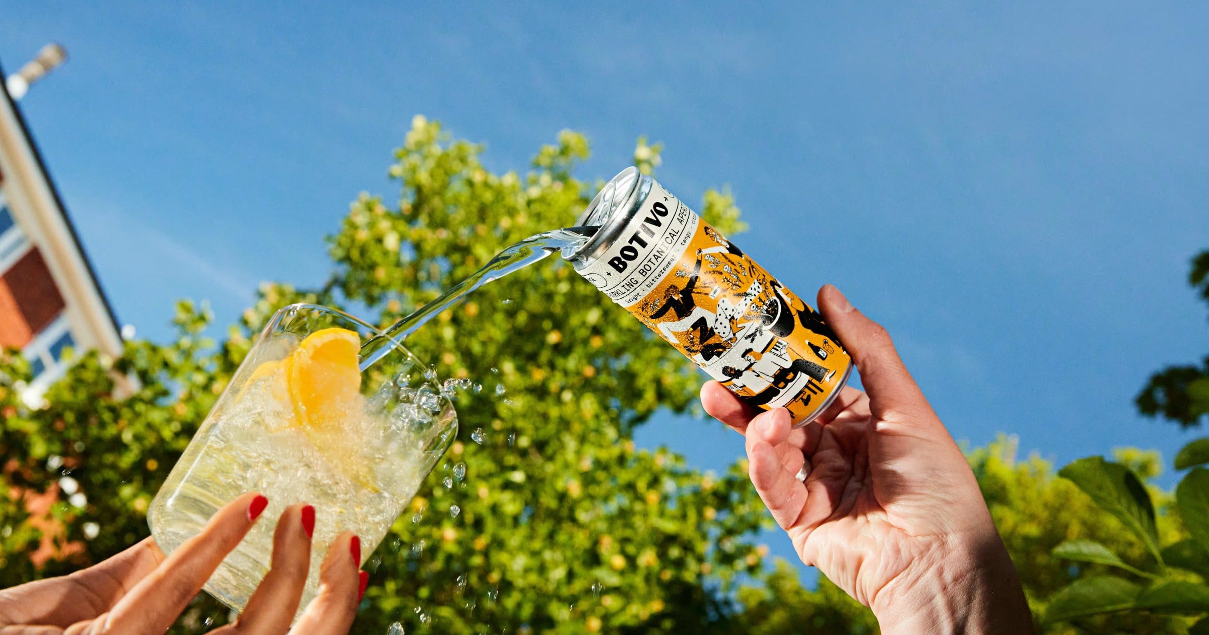 Botivo canned botanical aperitivo spritz being poured over ice, showing the brand's illustrated yellow label.